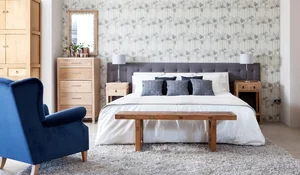 Dormitorio con cabecero de tela y funda nórdica blanca con cojines grises