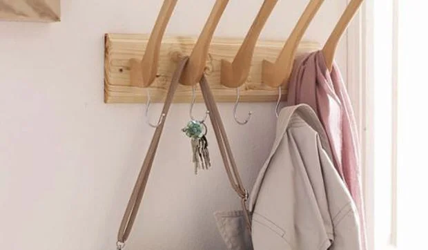 Perchero de pared realizado con perchas de madera
