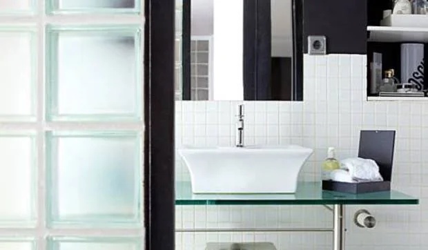 Un baño con muros de pavés, decorado en blanco y negro