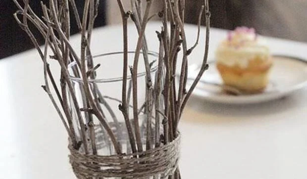 Un candelero navideño con ramas secas y velitas de té